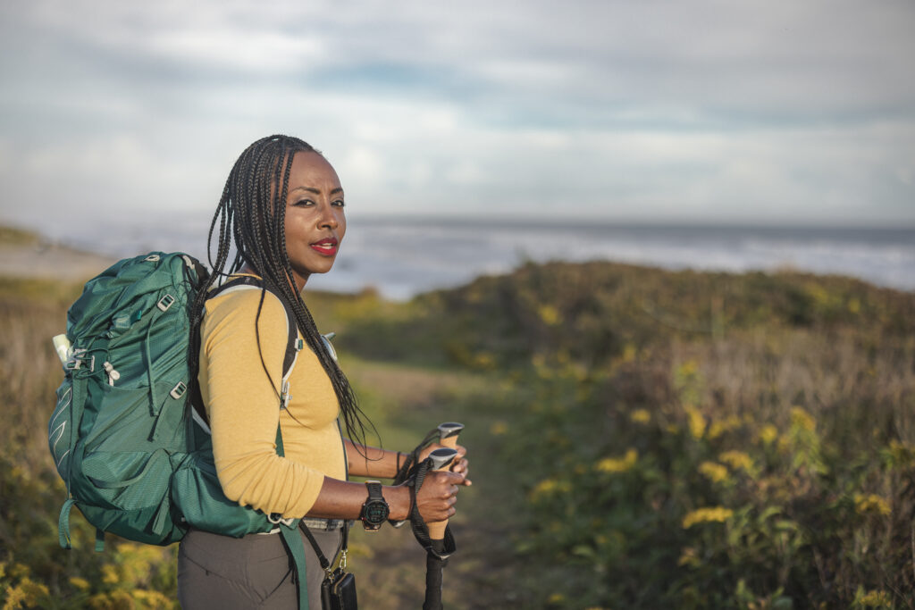 Mylena Sutton A frustrated African American woman with hiking poles on a hiking trail and showing a little teeth sucking rage.