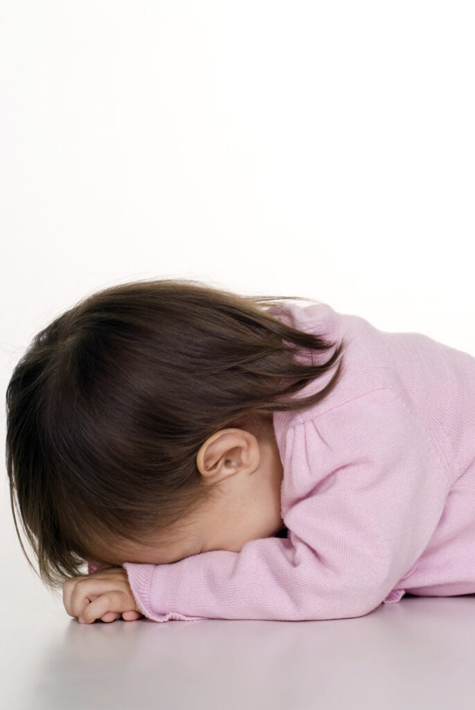 A child resting her head on her arms, representing the struggle of how to stick to your goals when temptation wins.
