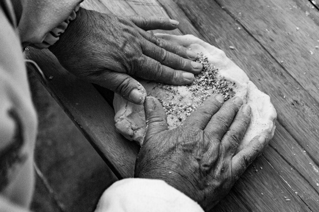 Weathered hands kneading dough representing a lifetime of sacrifice, giving without boundaries, and tired of helping others resentment.